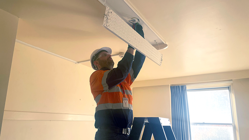 A Ventia employee installing LED lighting in a lamp fixture