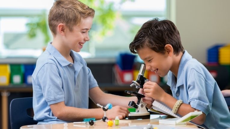 Two boys looking into a microscope 