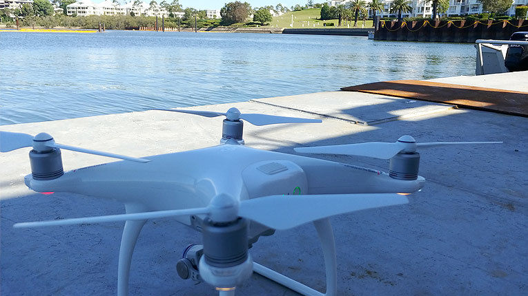 White drone pictured on cement floor beside water in Kendall Bay