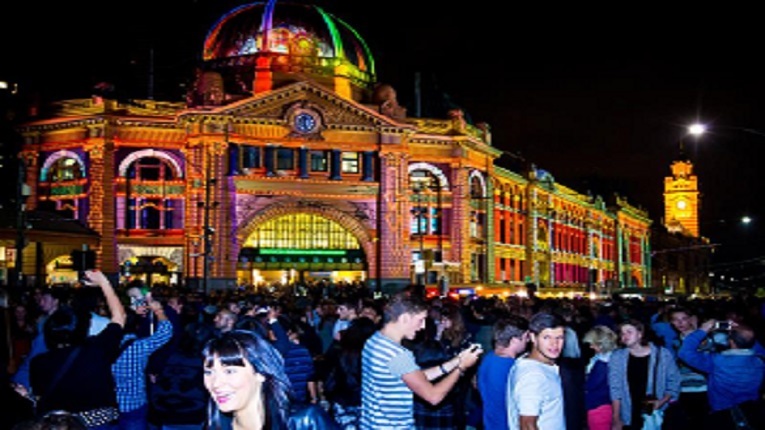 Bright building in Melbourne at night surrounded by event crowds