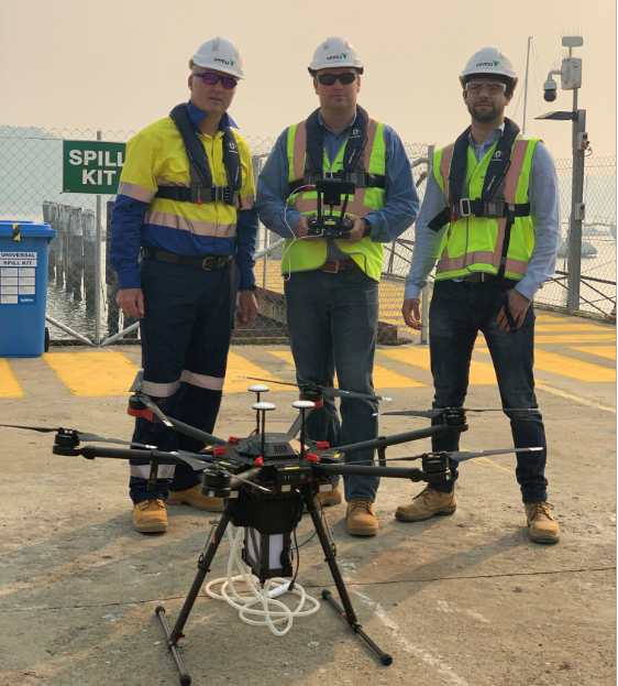 Three individuals pictured with drone at work-site